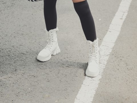 Jambes portant des bottes hautes blanches avec un jean