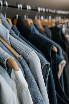 Portant de vêtements en denim suspendus sur des cintres en bois dans une boutique