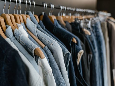 Portant de vêtements en denim suspendus sur des cintres en bois dans une boutique