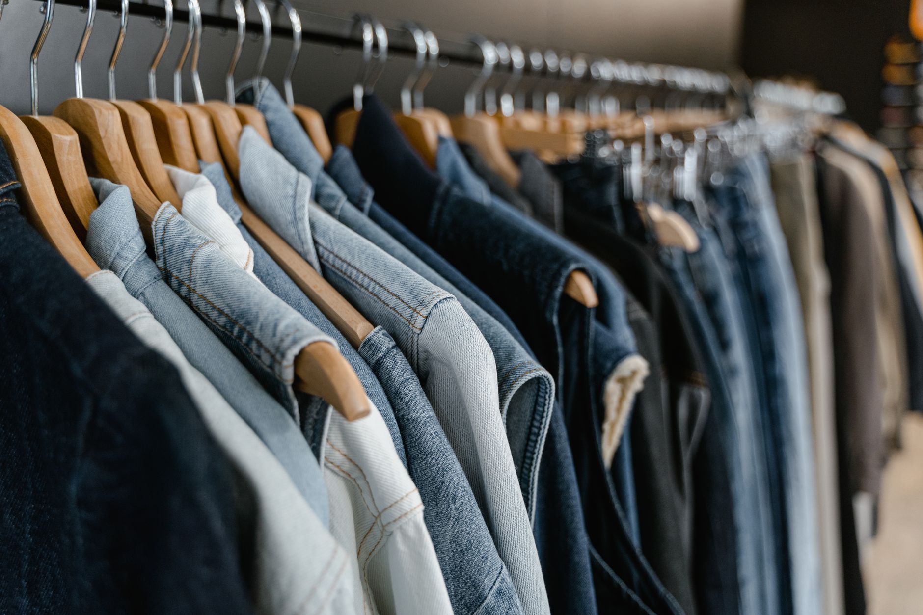 Portant de vêtements en denim suspendus sur des cintres en bois dans une boutique