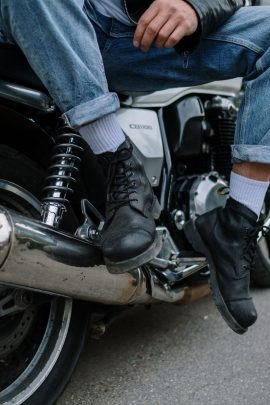 Bottes biker en cuir noir, pieds posés sur une moto, style rock