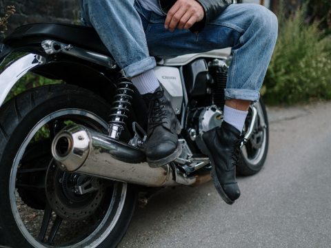 Bottes biker en cuir noir, pieds posés sur une moto, style rock