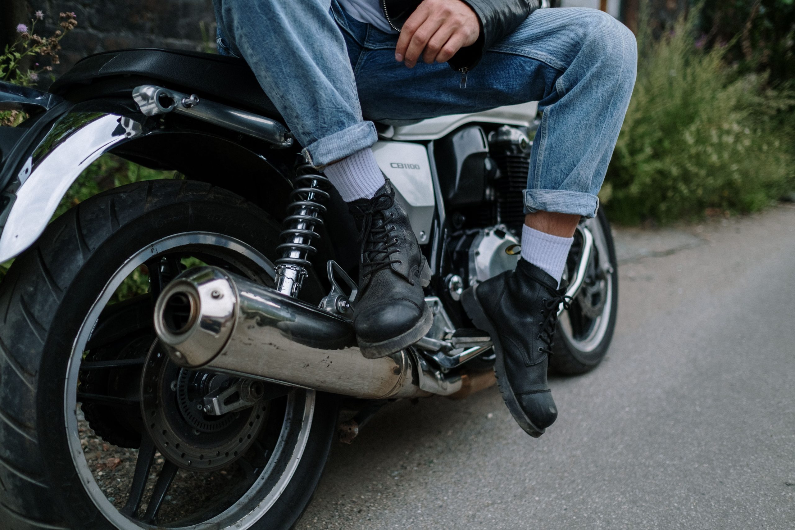 Bottes biker en cuir noir, pieds posés sur une moto, style rock