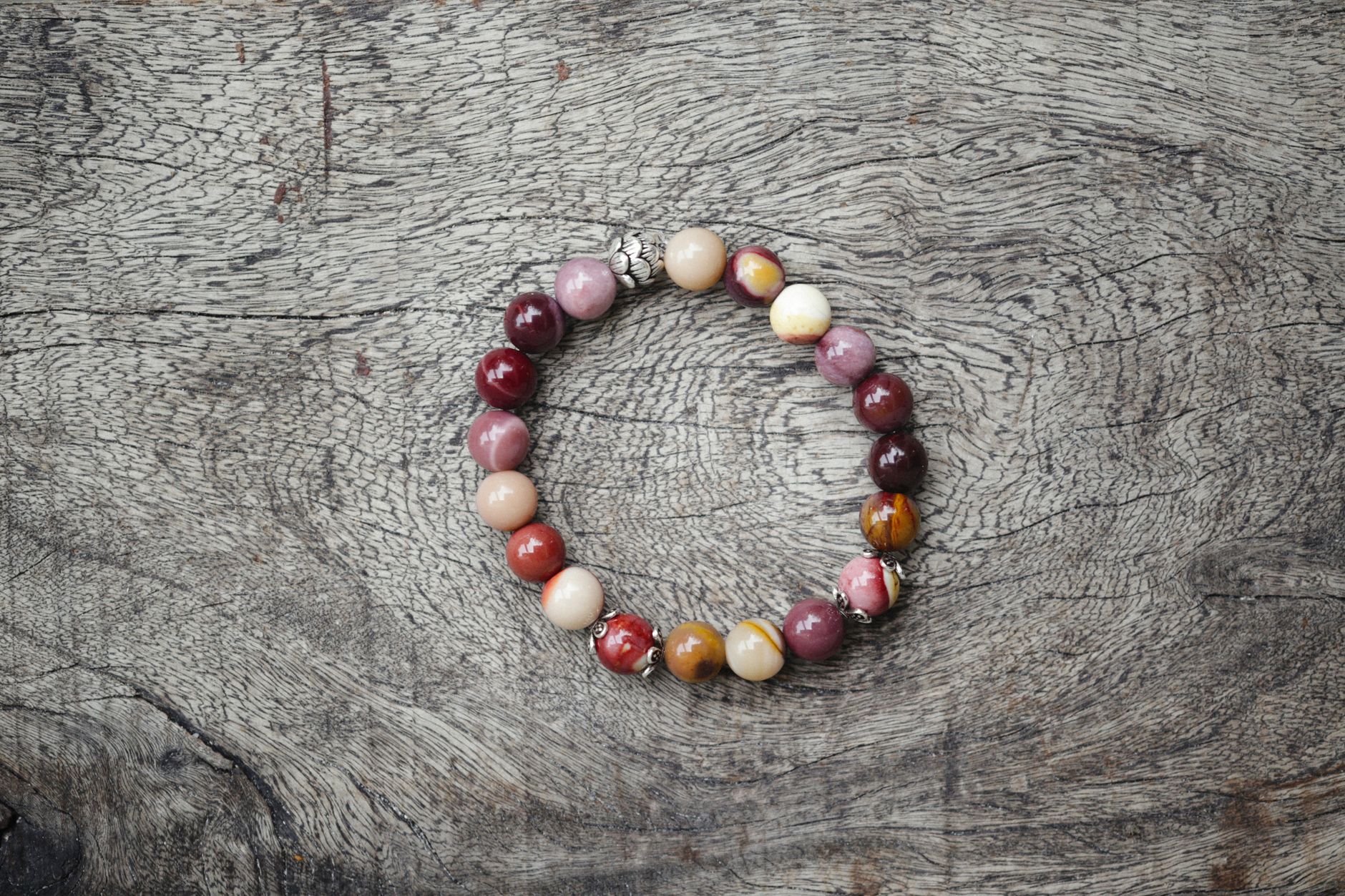 bracelet de perles rondes en pierre naturelle posé sur une planche de bois