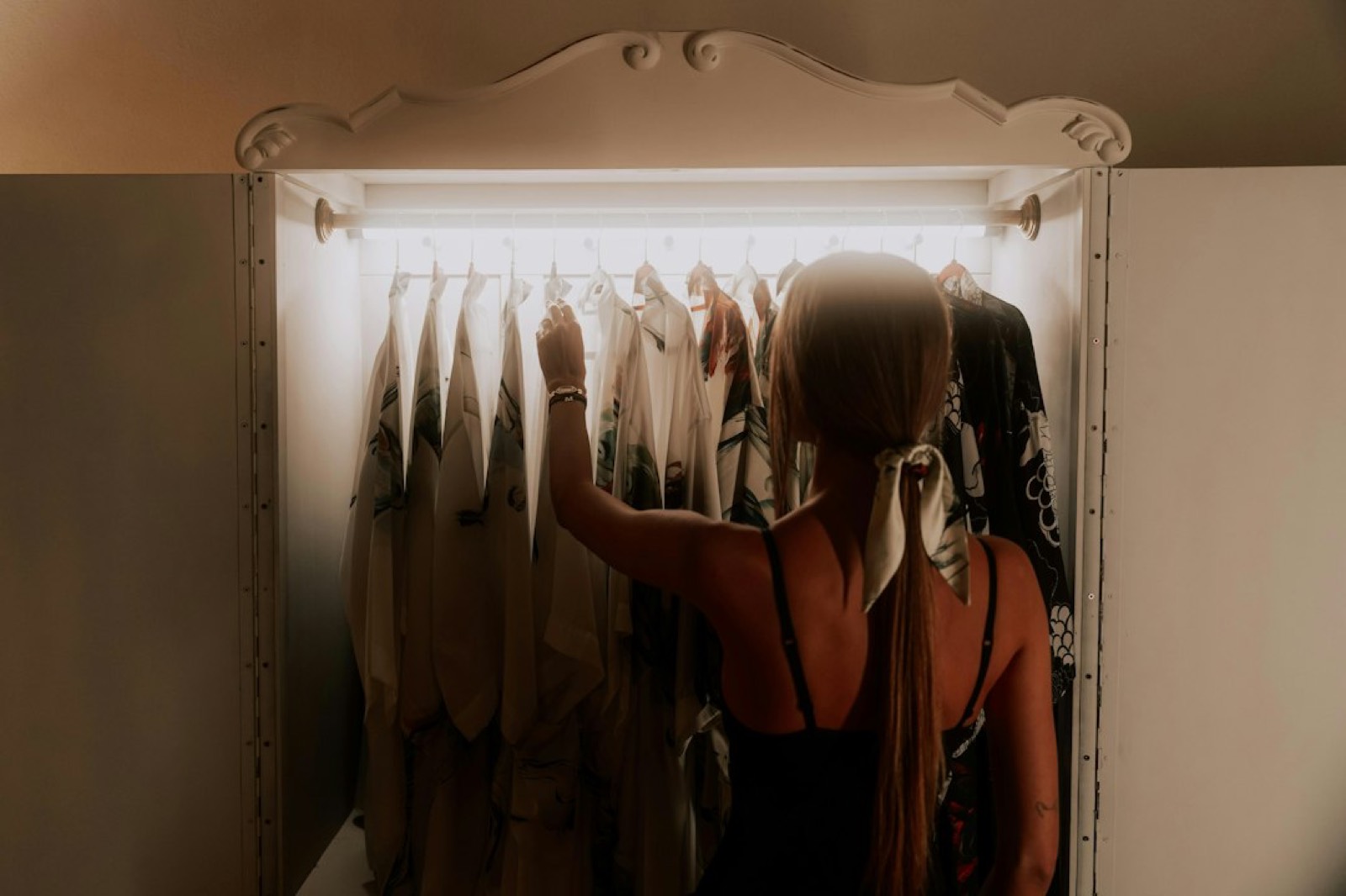 Penderie ouverte avec vêtements sur cintres devant un miroir